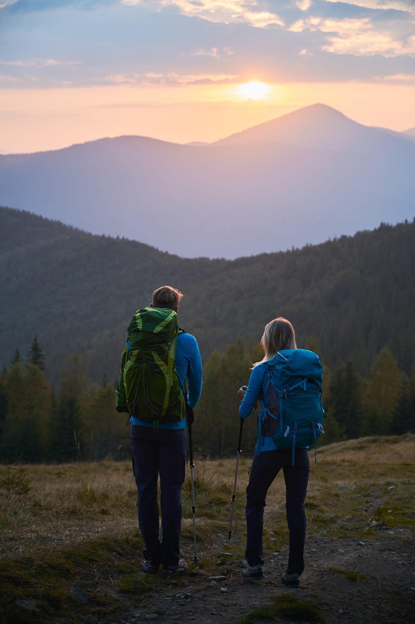 Two hikers looking at mountains at sunset